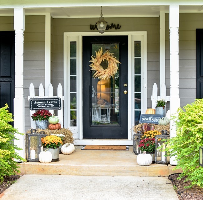 Farmhouse fall front porch with lots of mums, hay and pumpkins-16