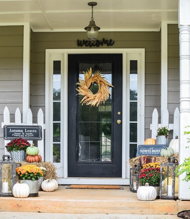 Farmhouse fall front porch with lots of mums, hay and pumpkins-17