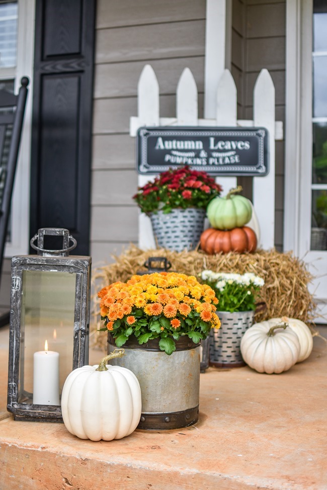 Farmhouse fall front porch with lots of mums, hay and pumpkins-3