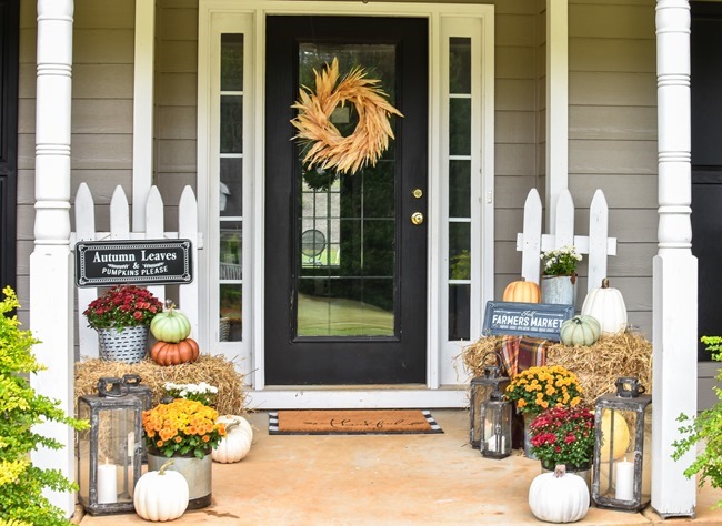 Farmhouse fall front porch with lots of mums, hay and pumpkins-31