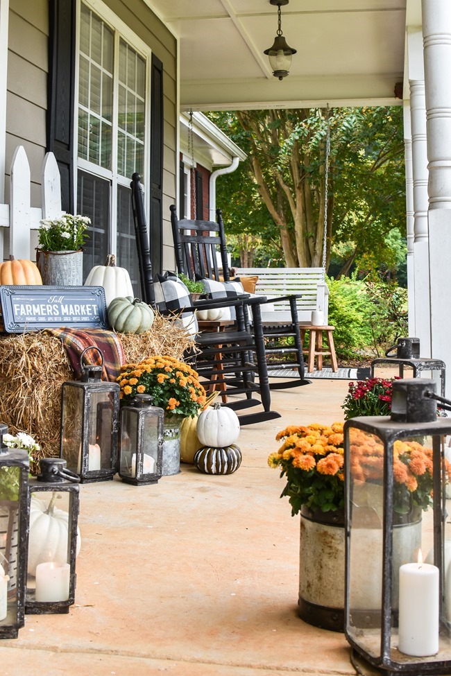 Farmhouse fall front porch with lots of mums, hay and pumpkins-39