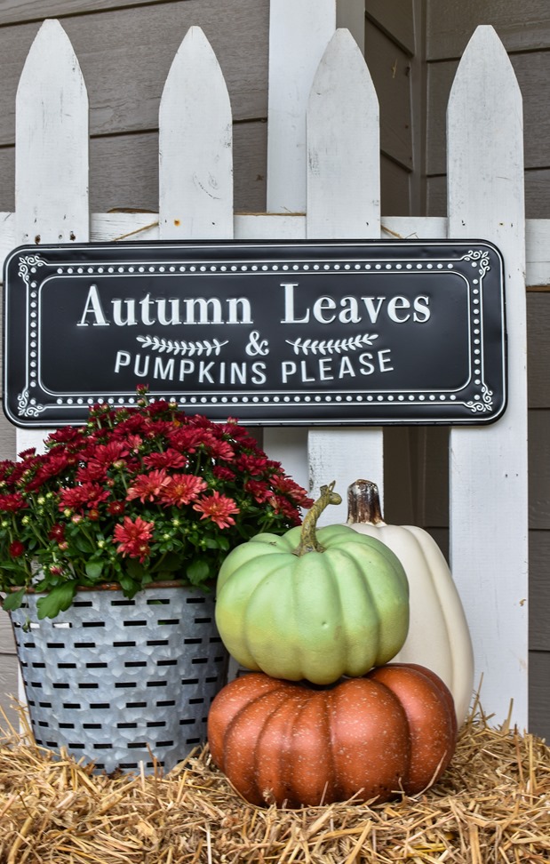 Farmhouse fall front porch with lots of mums, hay and pumpkins-40