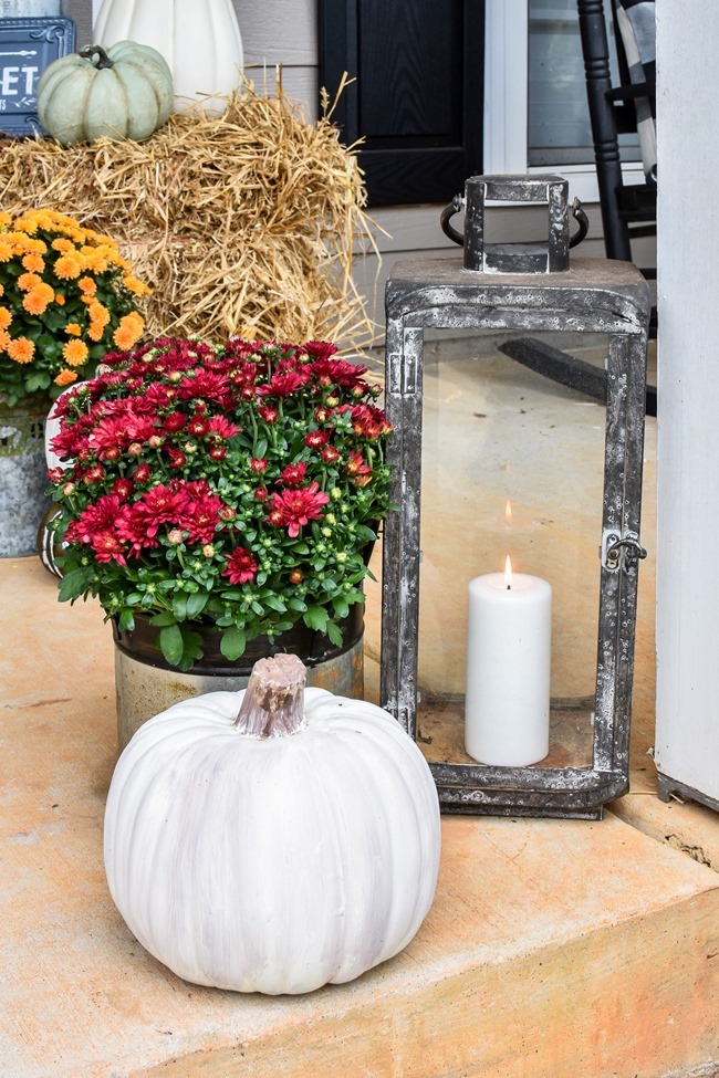 Farmhouse fall front porch with lots of mums, hay and pumpkins-42